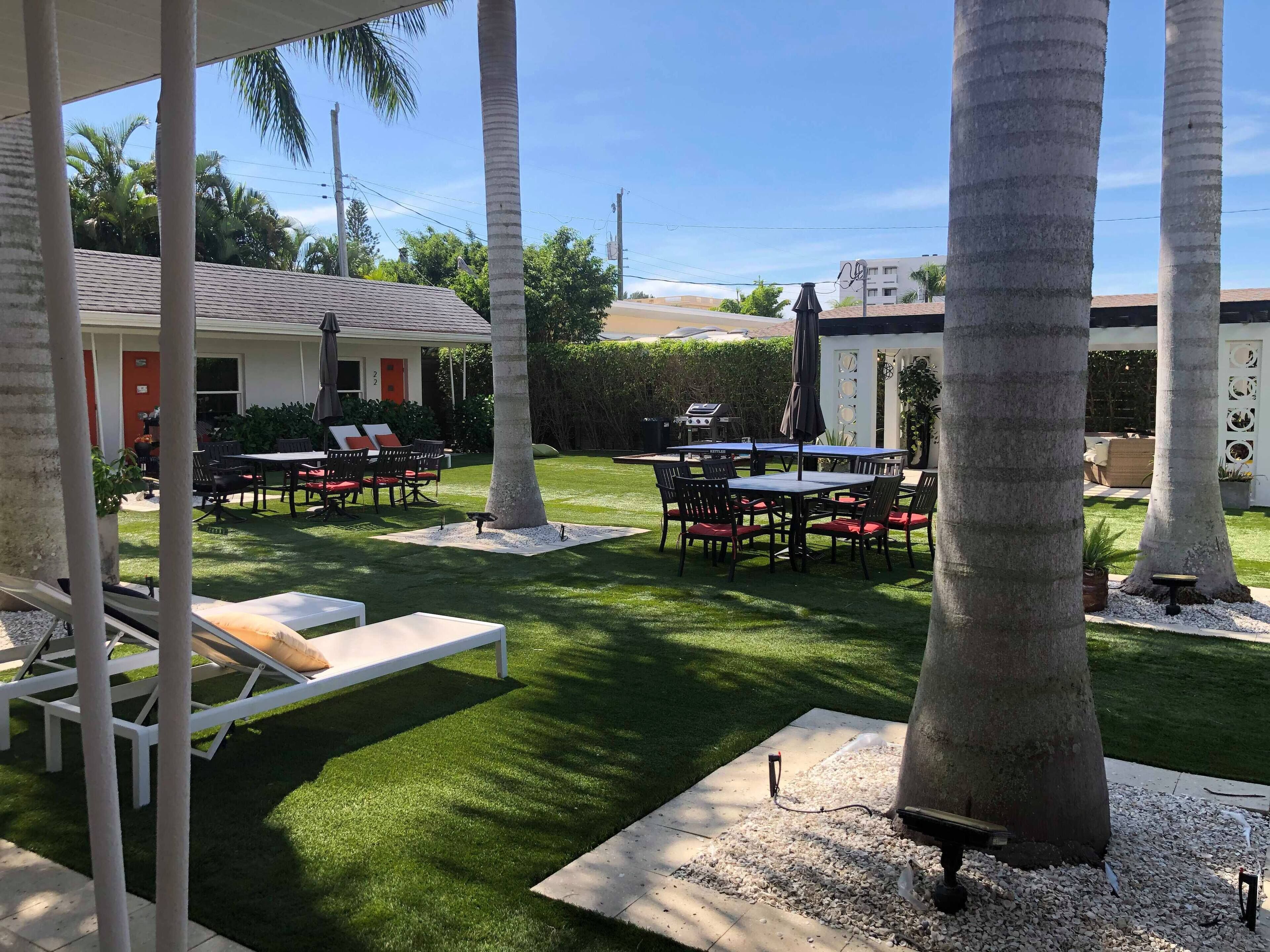 A patio area with a table and chairs, a grill, and a poolside lounge.