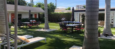 A patio area with a table and chairs, a grill, and a poolside lounge.