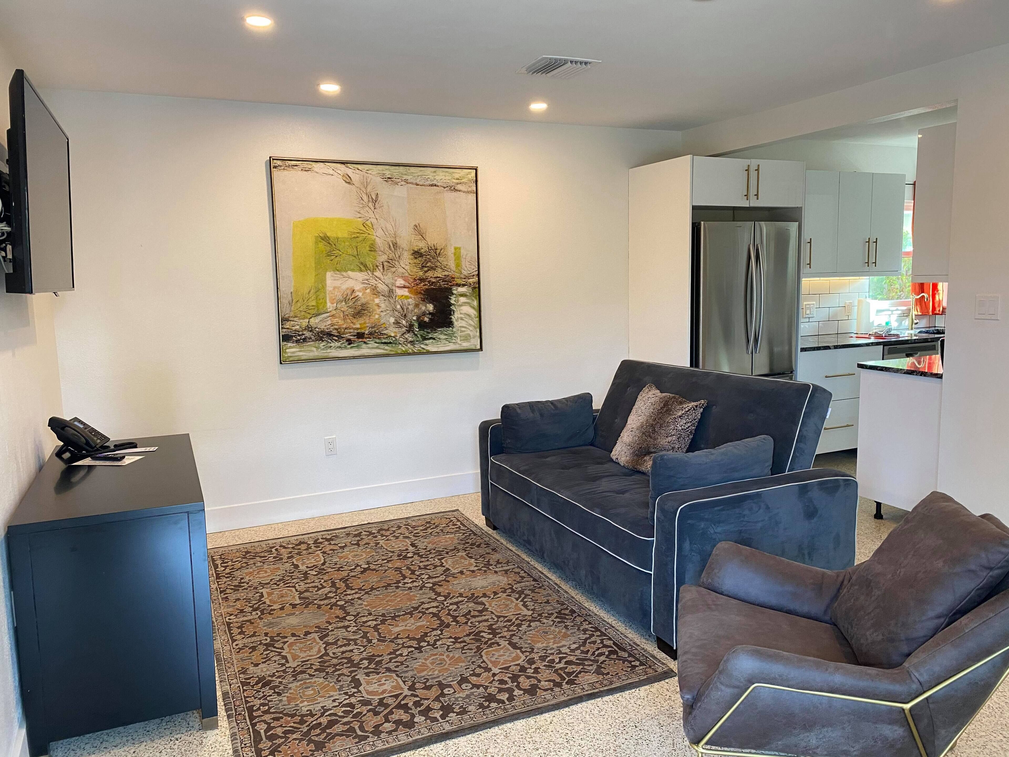 A modern living room with a dark blue sofa, a patterned rug, and a minimalist design.