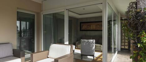 A modern living area with wicker furniture, a glass door leading to a balcony, and a framed artwork on the wall.