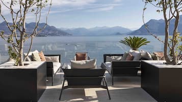 A modern outdoor seating area with a view of a lake and mountains.