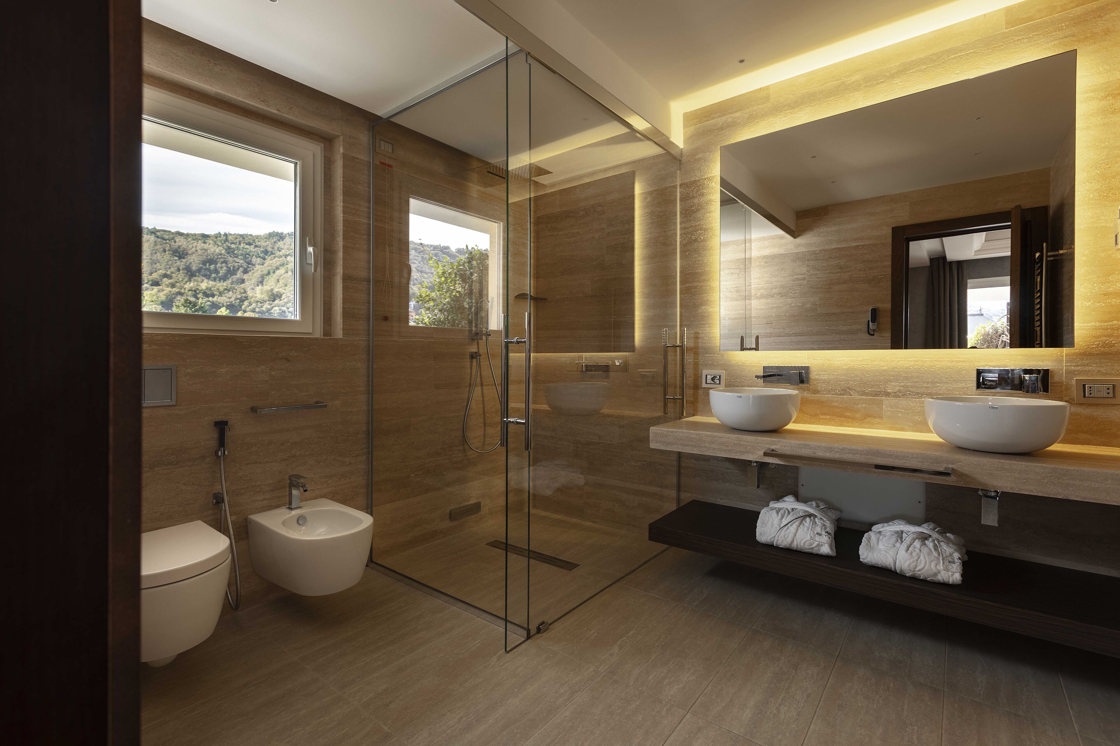 Un baño moderno con cabina de ducha de vidrio, un bidé y un espejo grande.