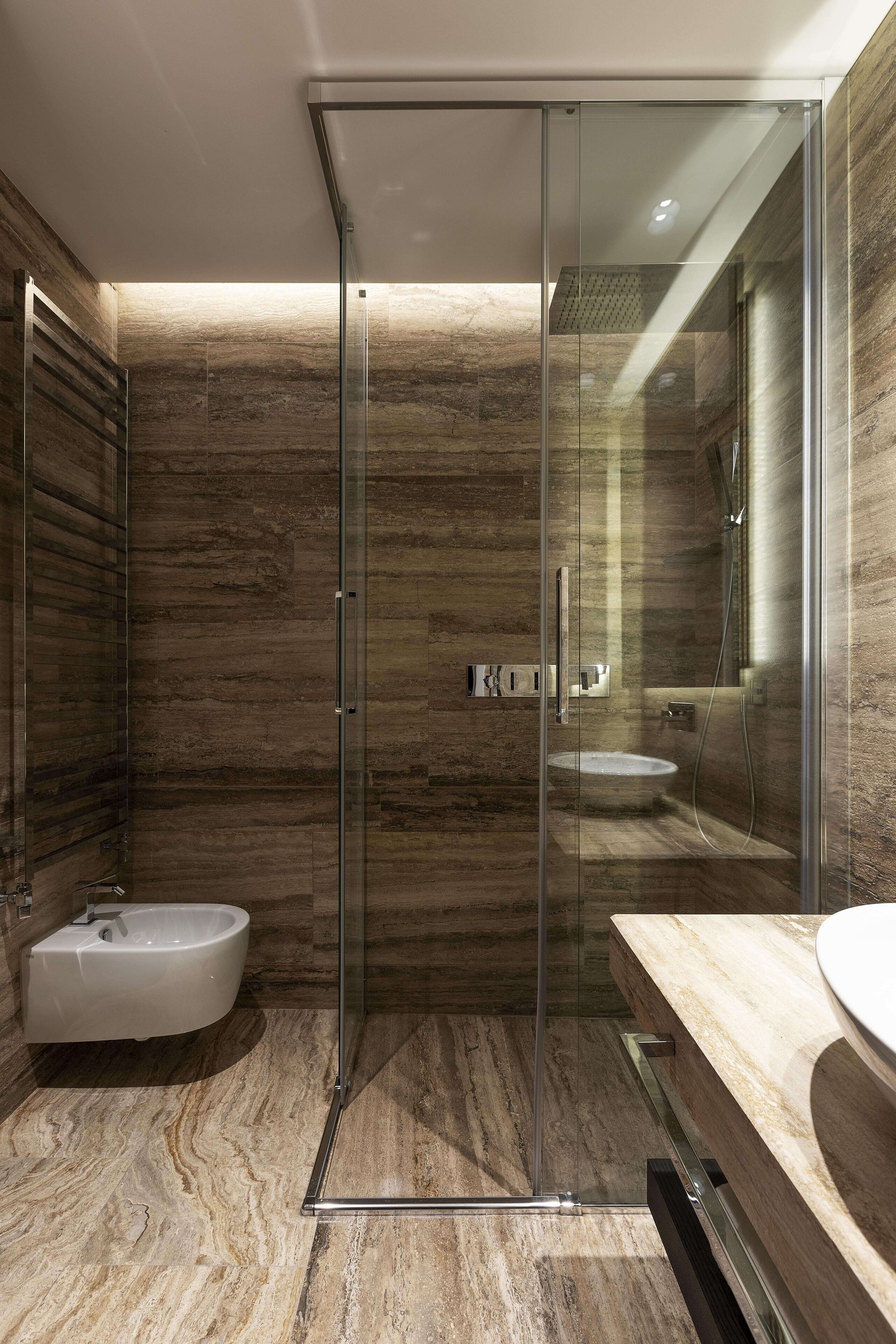 Une salle de bain moderne dotée d’une douche à parois de verre, d’une baignoire sur pieds et d’un meuble-lavabo en marbre.