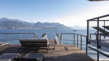 Una terraza de madera con sillones de descanso y vistas al mar y a las montañas.