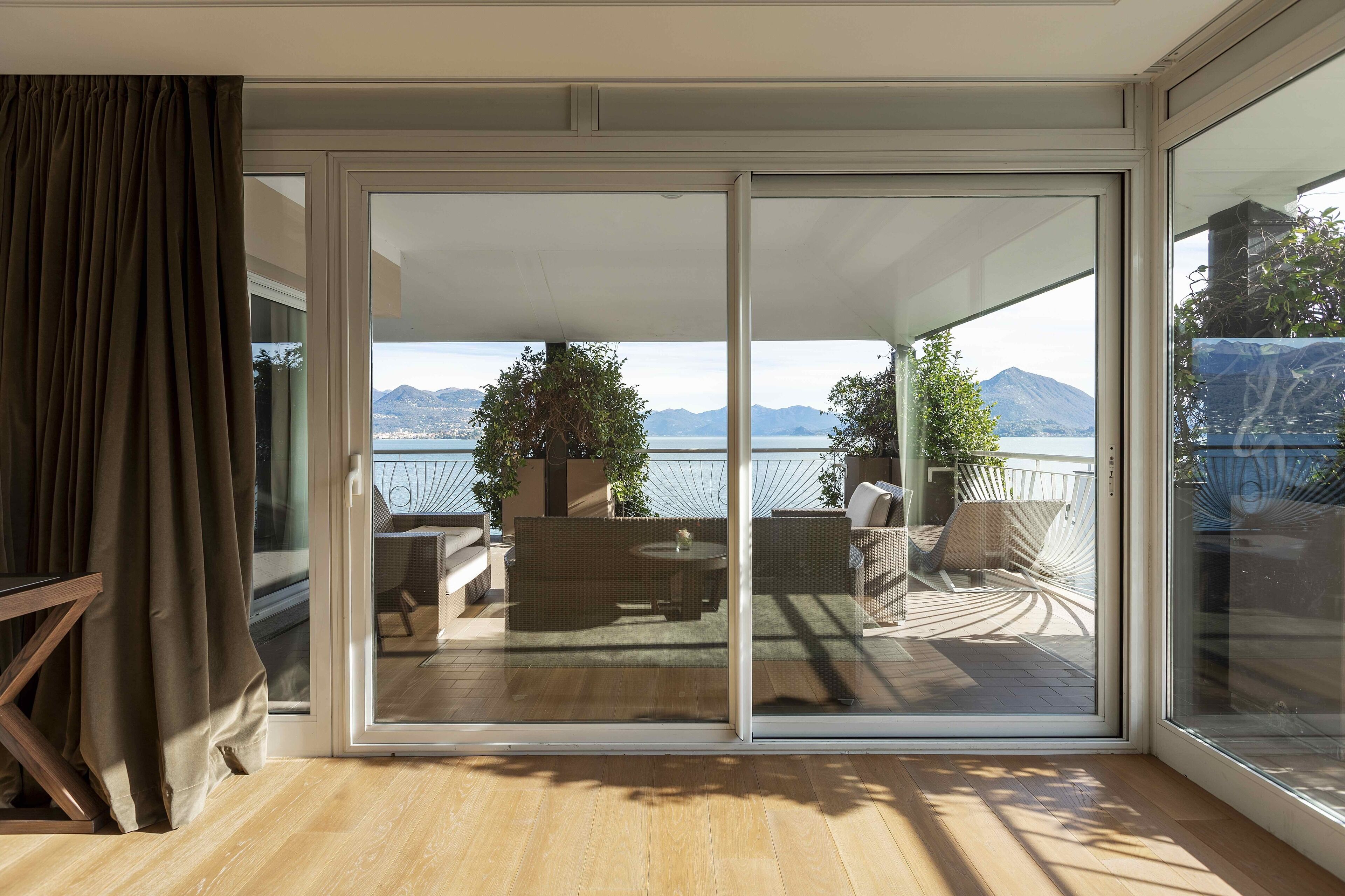 Una habitación con puerta de vidrio corrediza que da a un patio exterior con vistas a montañas y una masa de agua.