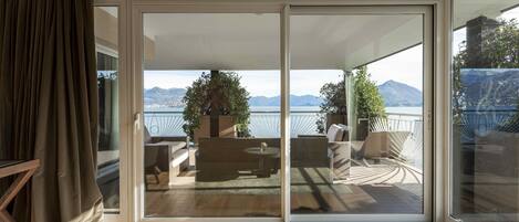 Una habitación con puerta de vidrio corrediza que da a un patio exterior con vistas a montañas y una masa de agua.