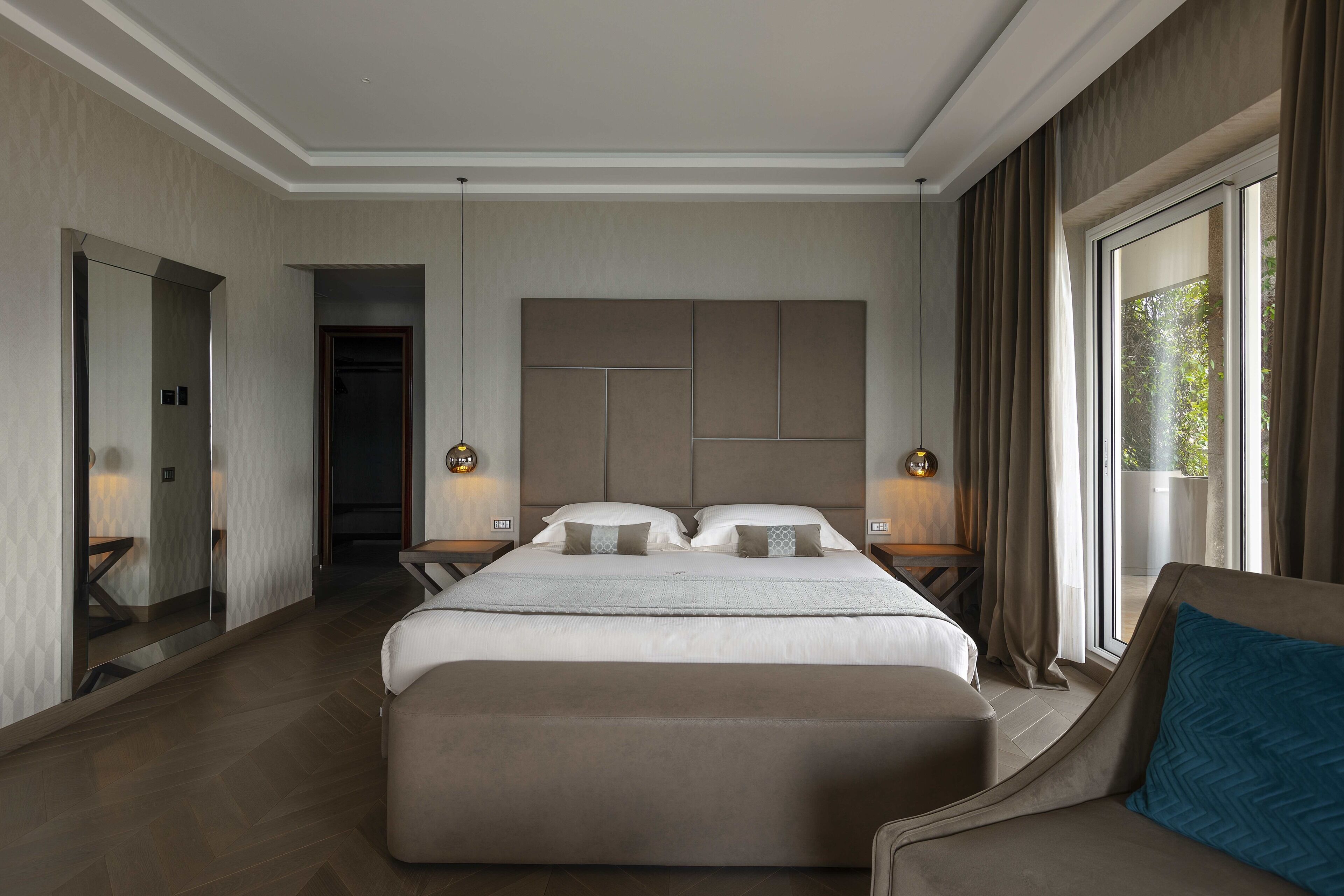 A modern hotel room with a large bed, a seating area, and a view of the outdoors.