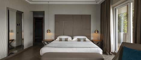 A modern hotel room with a large bed, a seating area, and a view of the outdoors.