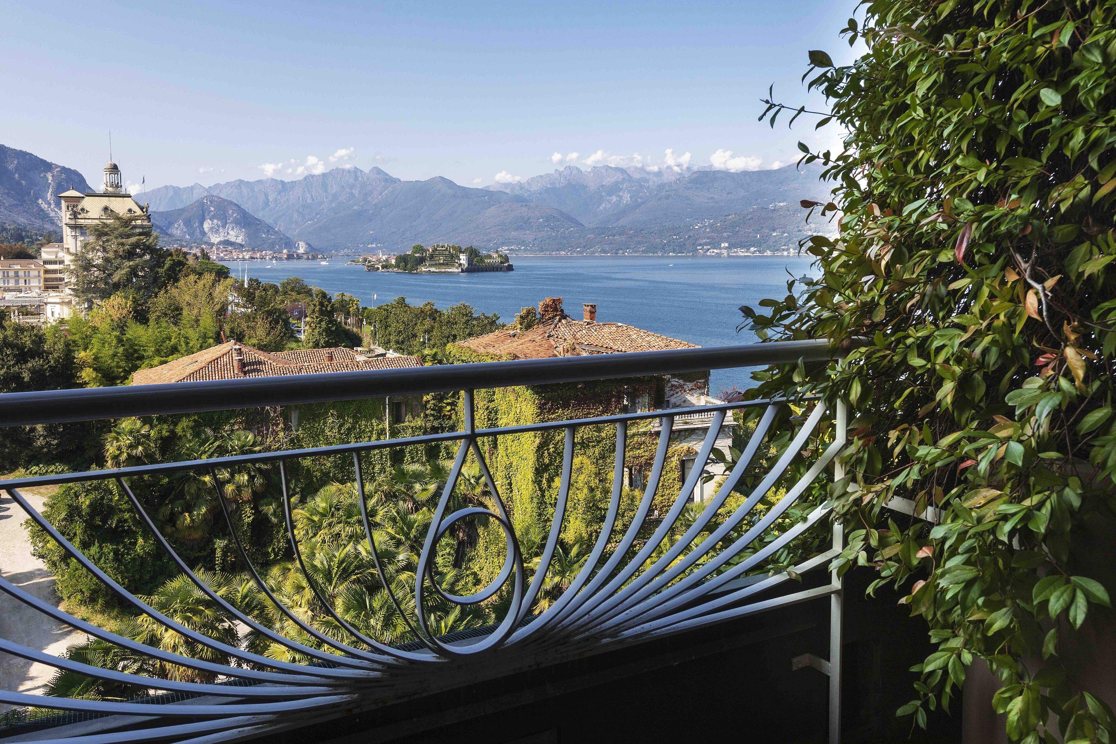 A balcony with a view of a lake, mountains, and a distant island.