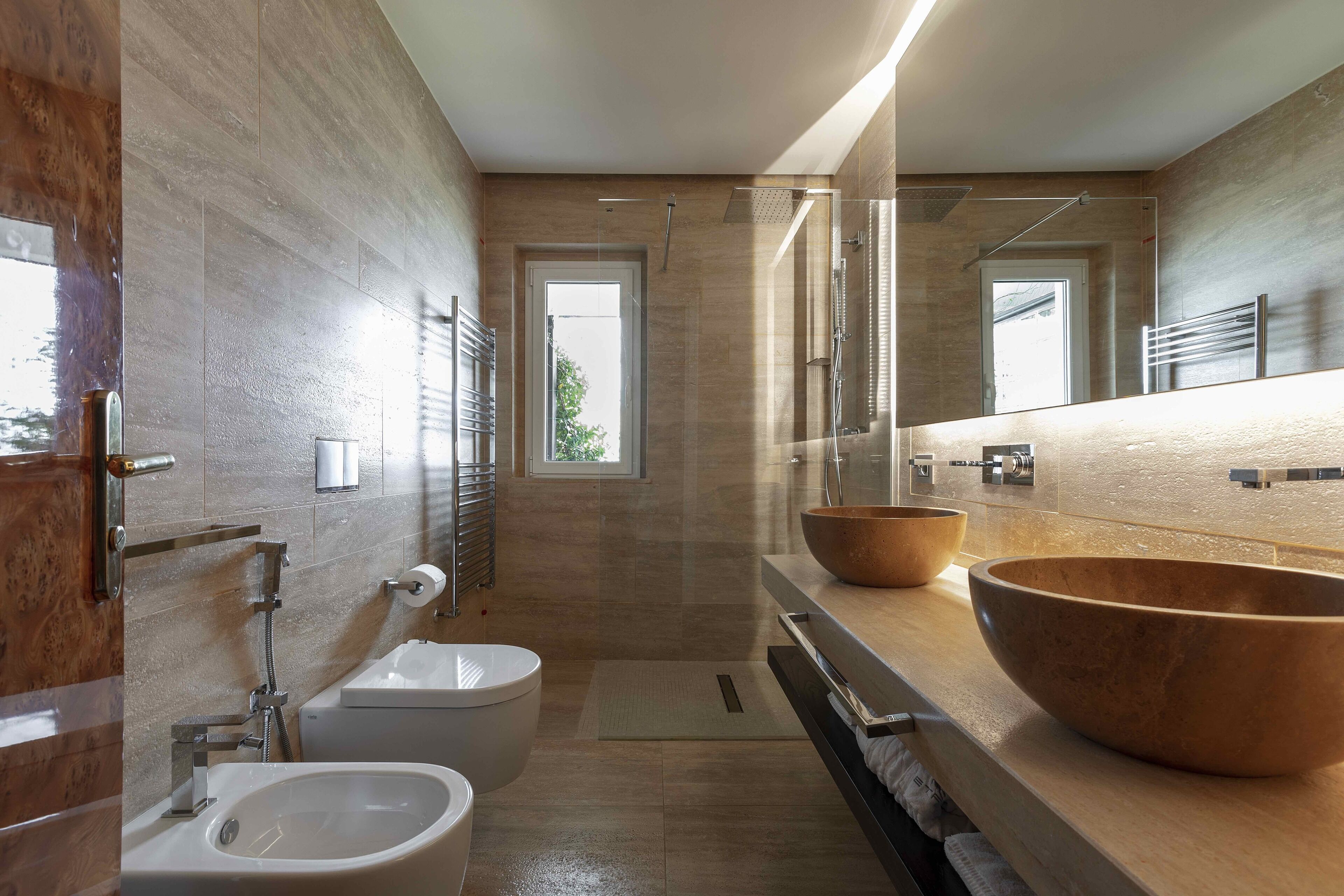 Un baño moderno con un espejo grande, dos lavamanos, inodoro y ducha.