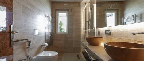A modern bathroom with a large mirror, two sinks, a toilet, and a shower.