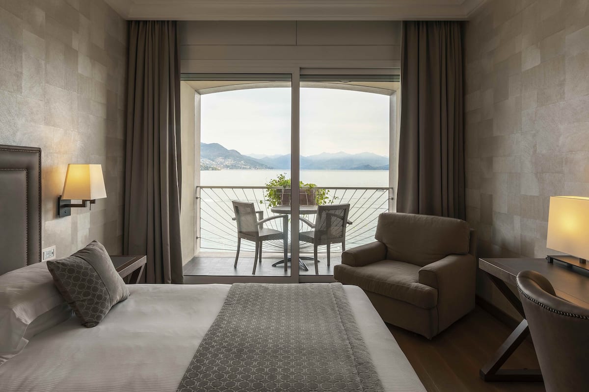 Ein Hotelzimmer mit einem großen Bett, einem Sofa, einem Sessel, einem Tisch und einem Balkon mit Bergblick.