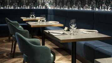 A restaurant interior with dark blue upholstered seating, wooden tables, and teal chairs.