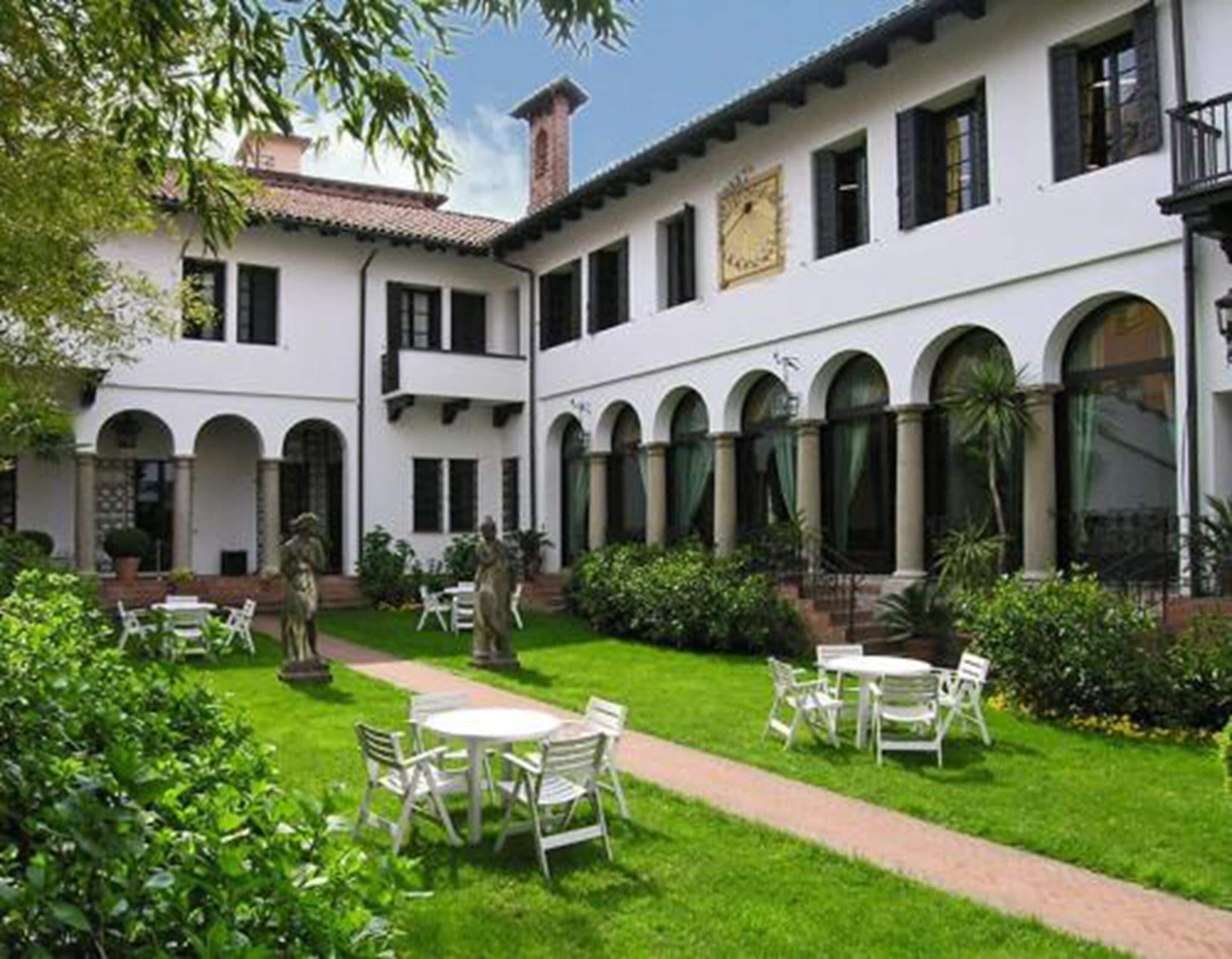 Un patio con paredes blancas, ventanas arqueadas y zonas de estar al aire libre.