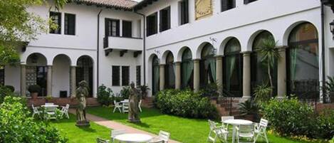 Un patio con paredes blancas, ventanas arqueadas y zonas de estar al aire libre.