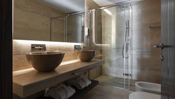 A modern bathroom with a large mirror, two large bowls on the vanity, a glass shower enclosure, and a white toilet.