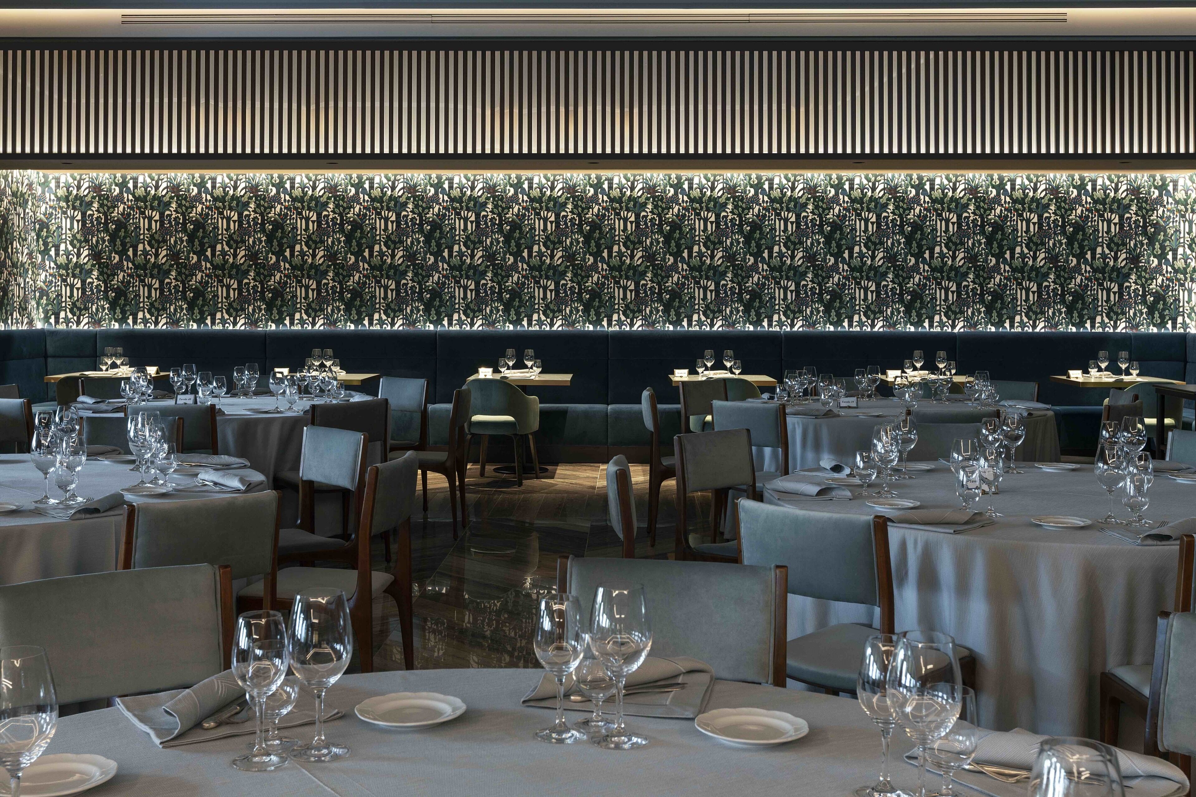 A restaurant with multiple tables set for dining, featuring a patterned wall and a modern design.
