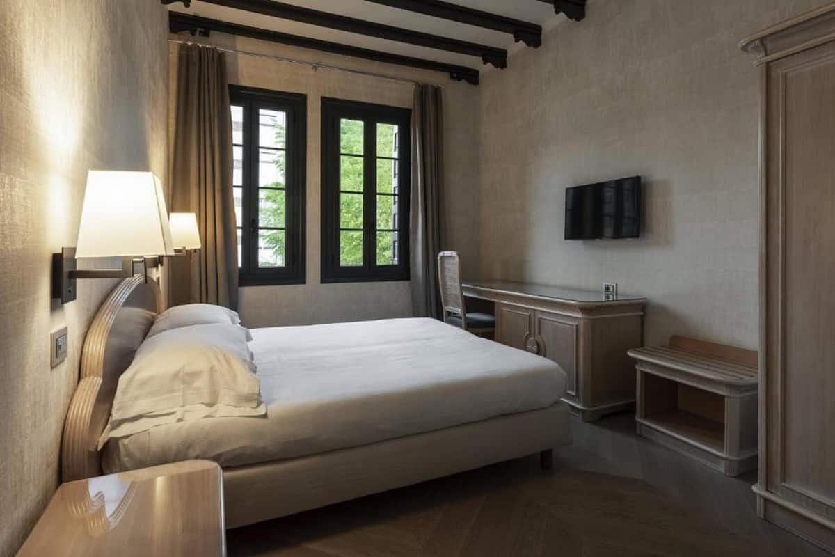 Ein Schlafzimmer mit Bett, Nachttischlampen, Schreibtisch, Stuhl, Fernseher und Kleiderschrank.