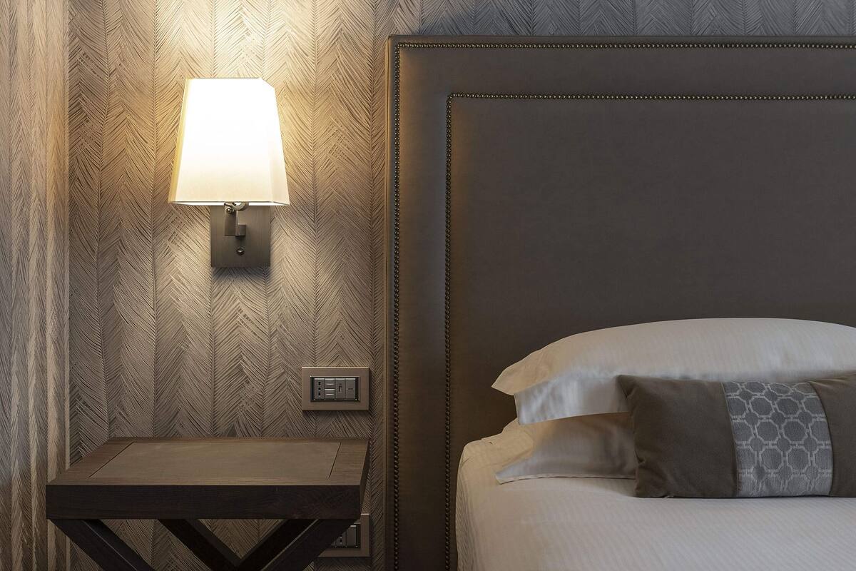 Ein Hotelzimmer mit einem Bett, einem Nachttisch mit Lampe und einer Wand mit Fischgrätmuster.