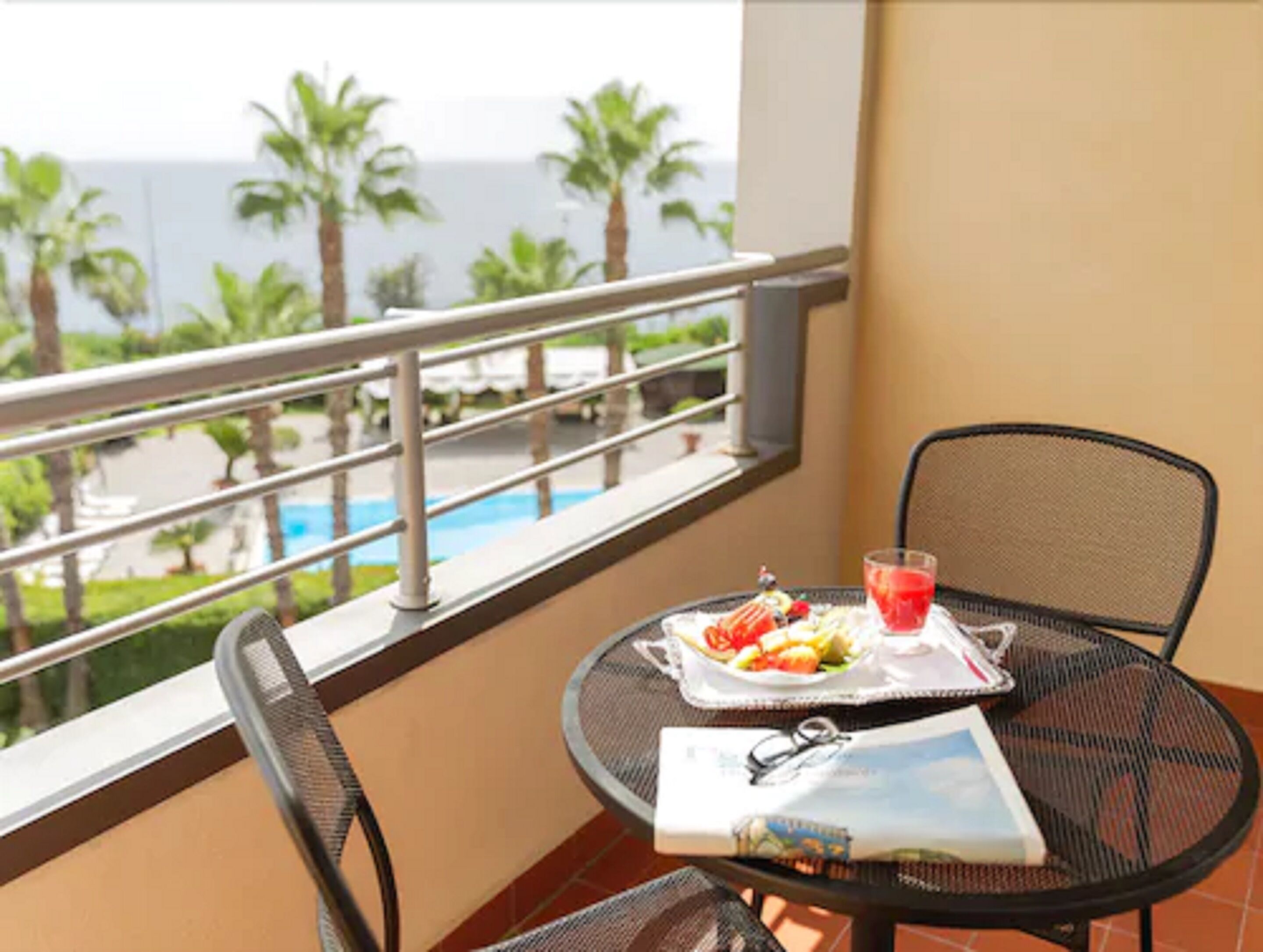 Un balcone con un tavolo apparecchiato per la colazione, una bevanda e un libro.
