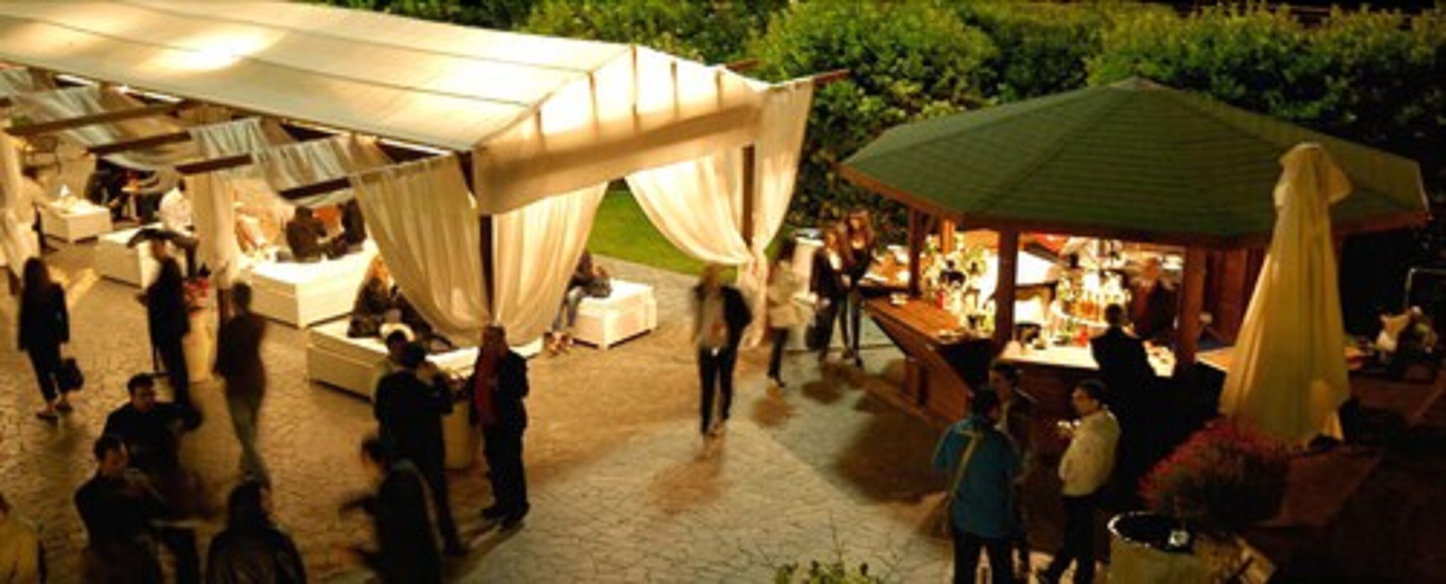 Evento al aire libre con carpas y mesas, probablemente un mercado o feria.