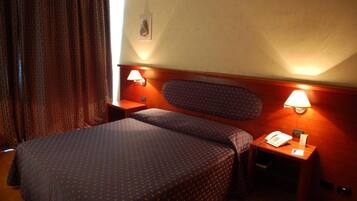 A hotel room with a bed, two bedside tables, and two wall-mounted lamps.