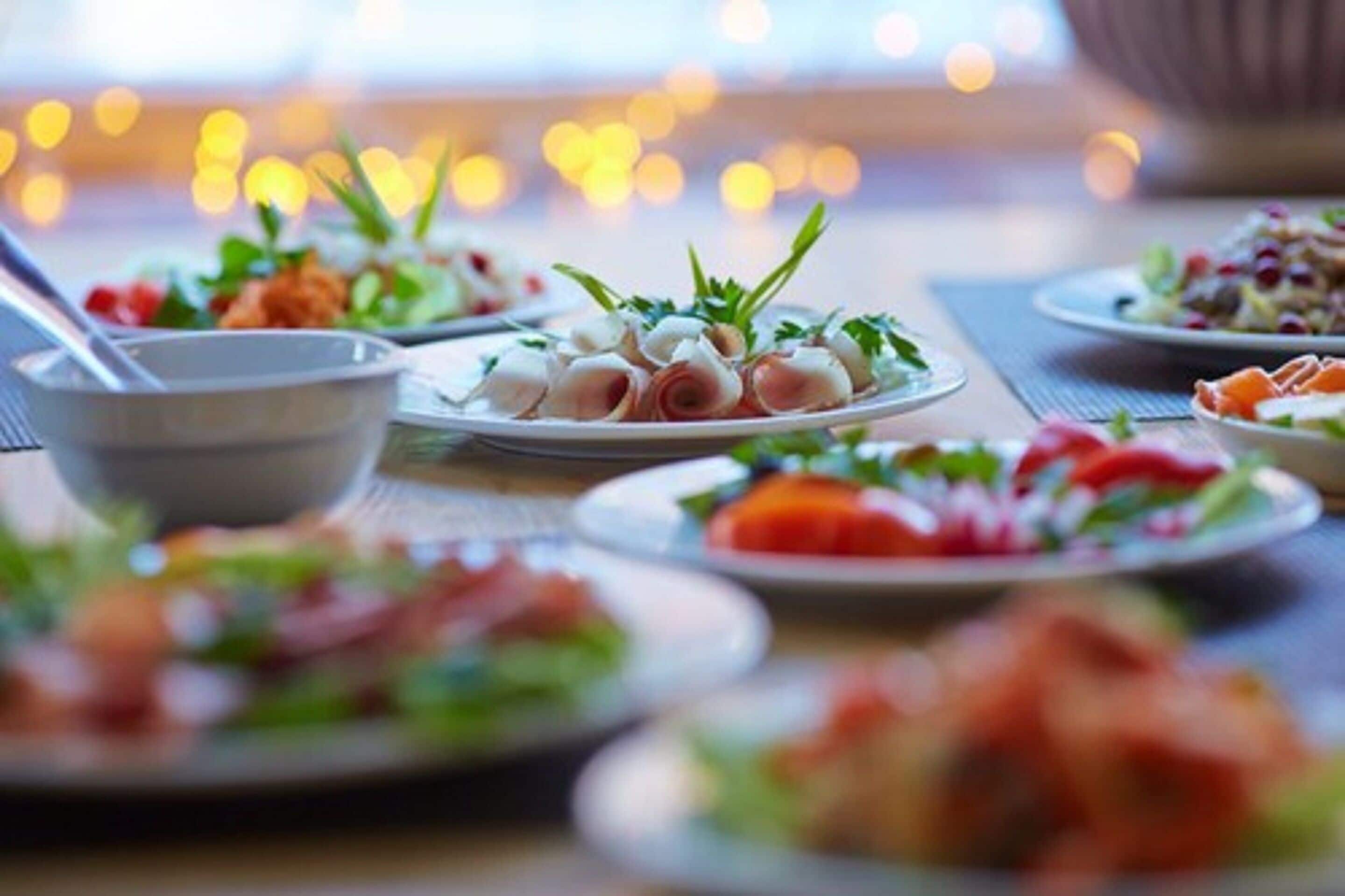 Uma mesa com diversos pratos, incluindo saladas e aperitivos, em uma área de jantar bem iluminada.