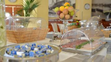 A buffet with various food items, including a glass bowl of fruit, a wicker basket, and a meat display.