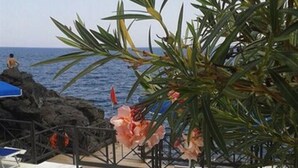 A beachside lounge area with blue lounge chairs and a view of the ocean. - Hotel Nettuno (Catania)