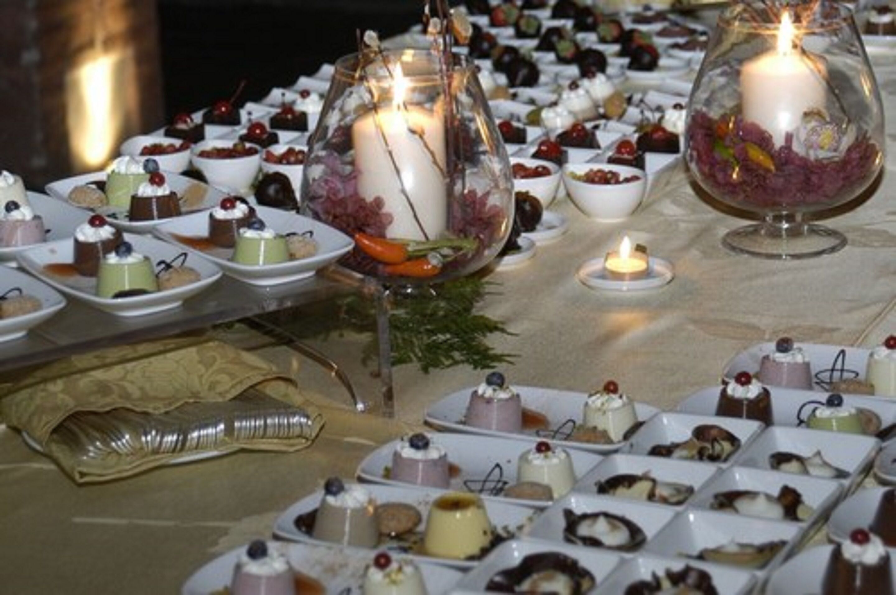 Una mesa dispuesta con diversos postres y un centro de mesa con vela.