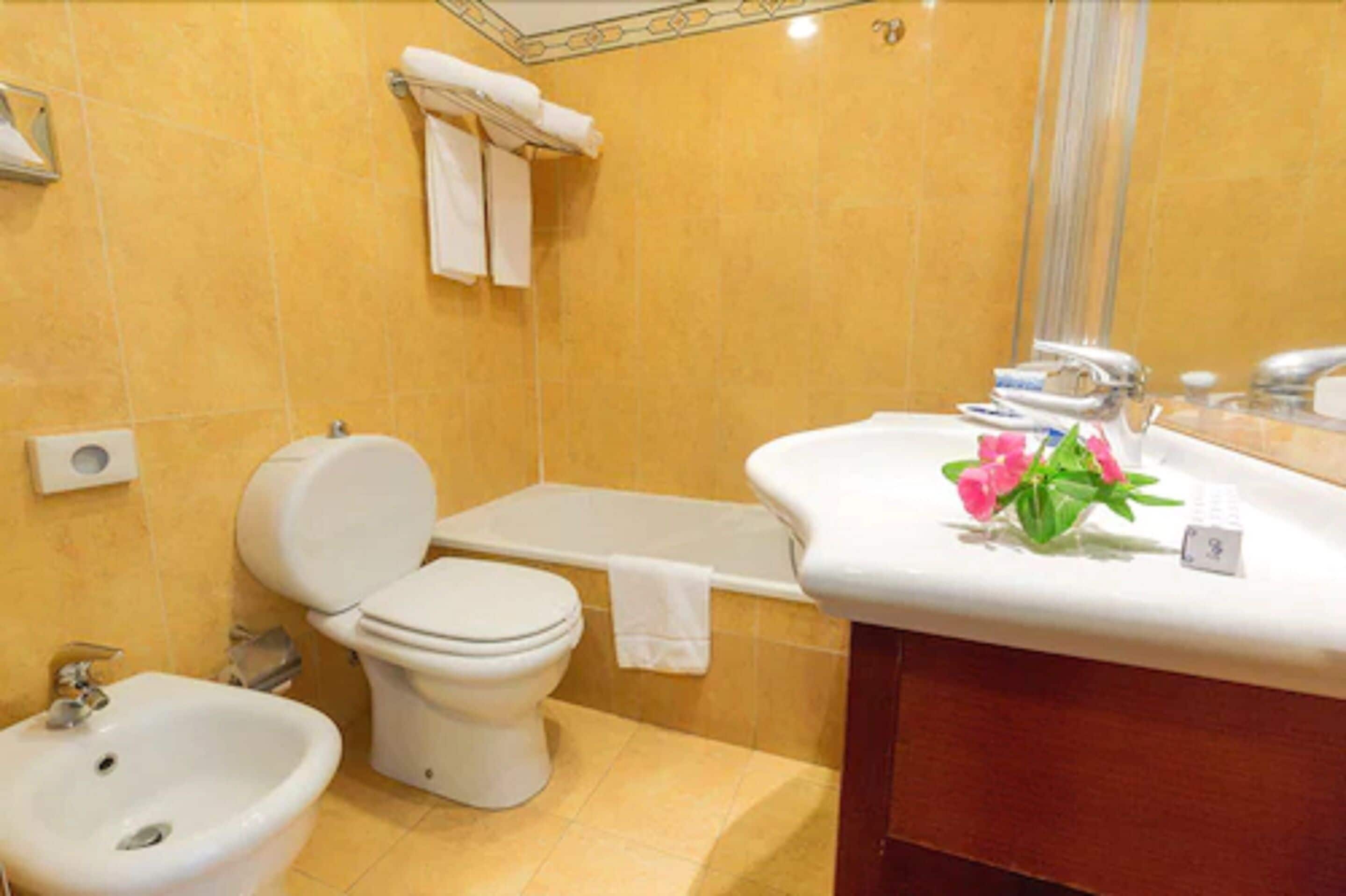 Un baño con inodoro, bidé, bañera y lavamanos.