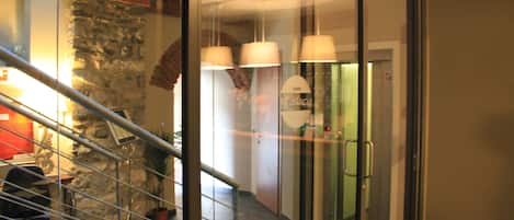 En hotellobby med en trappa, en stenmur och en receptionsdisk.