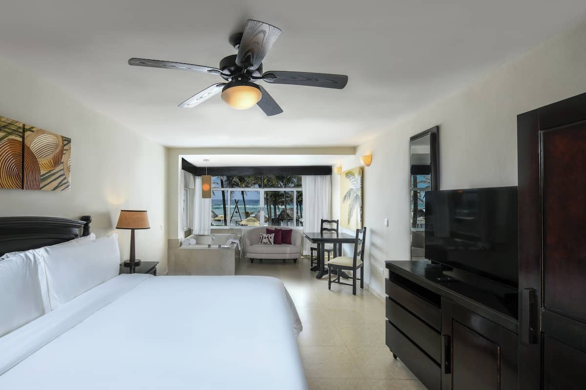 Una habitación de hotel con cama, escritorio, televisión y ventilador de techo.