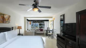 Una habitación de hotel con cama, escritorio, televisión y ventilador de techo.