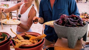 A couple dining at an outdoor market with terracotta pots and wooden tables.