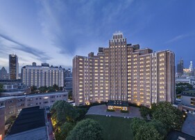 A multi-story hotel with a central courtyard, surrounded by other buildings.