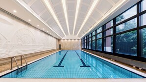 A large indoor swimming pool with a tiled floor, a vaulted ceiling, and large windows on one side. - Jin Jiang Hotel Shanghai (Shanghai)