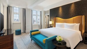 A hotel room with a large bed, a TV, a sofa, and a view of the city. - Jin Jiang Hotel Shanghai (Shanghai)