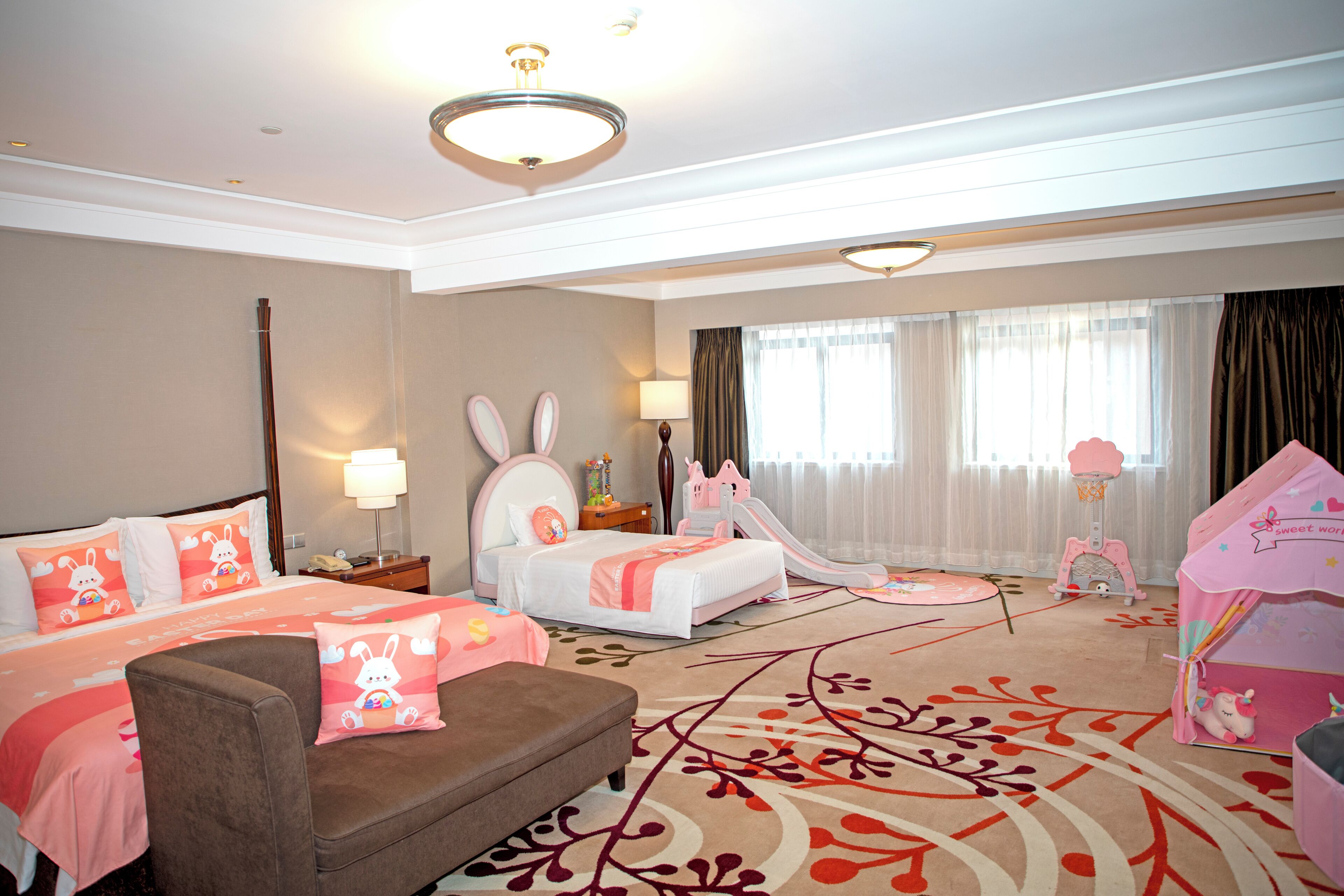 Habitación de hotel con dos camas, un sofá, una tienda de juegos y un tobogán.