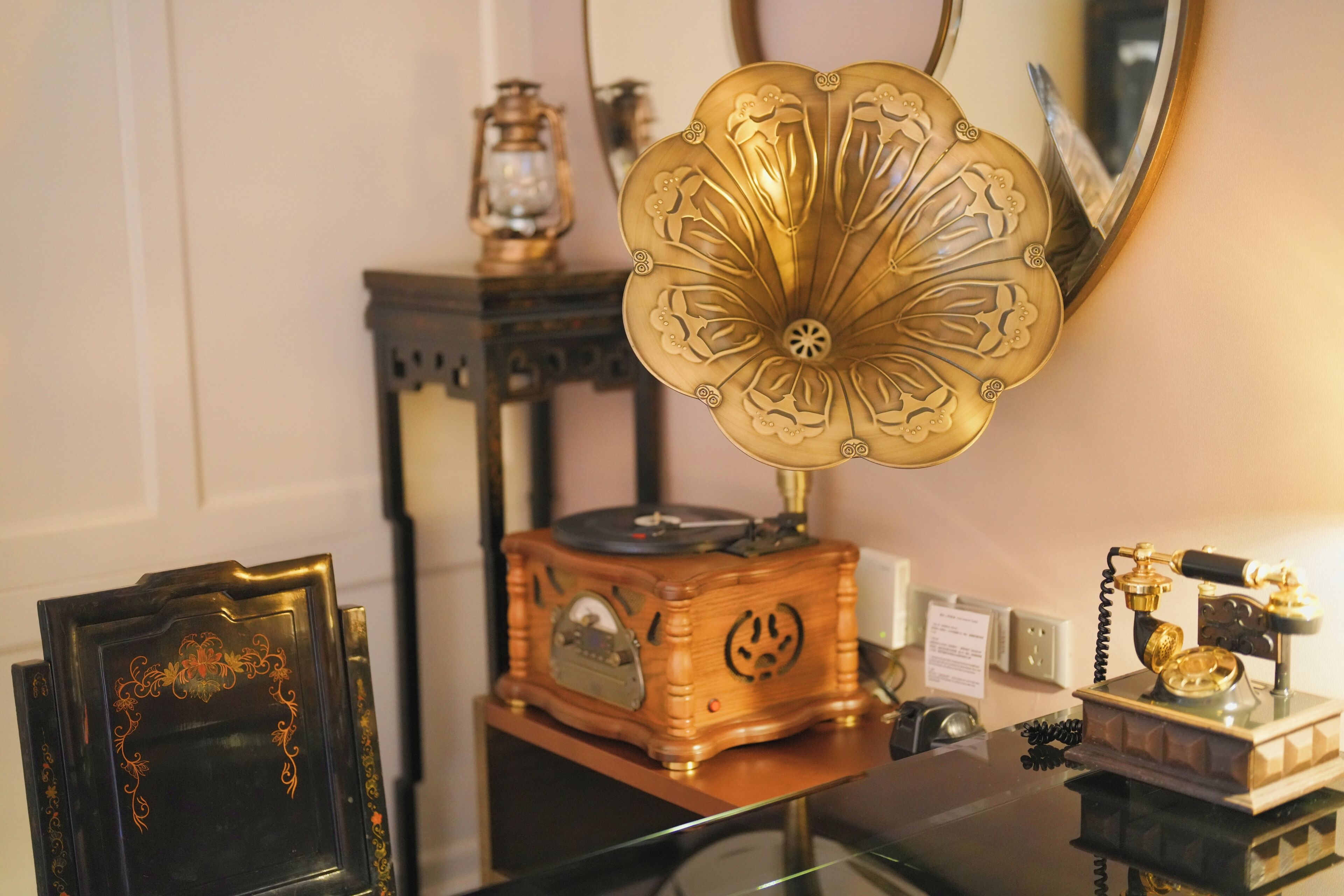 A vintage radio on a wooden table, a decorative mirror, and a framed picture.