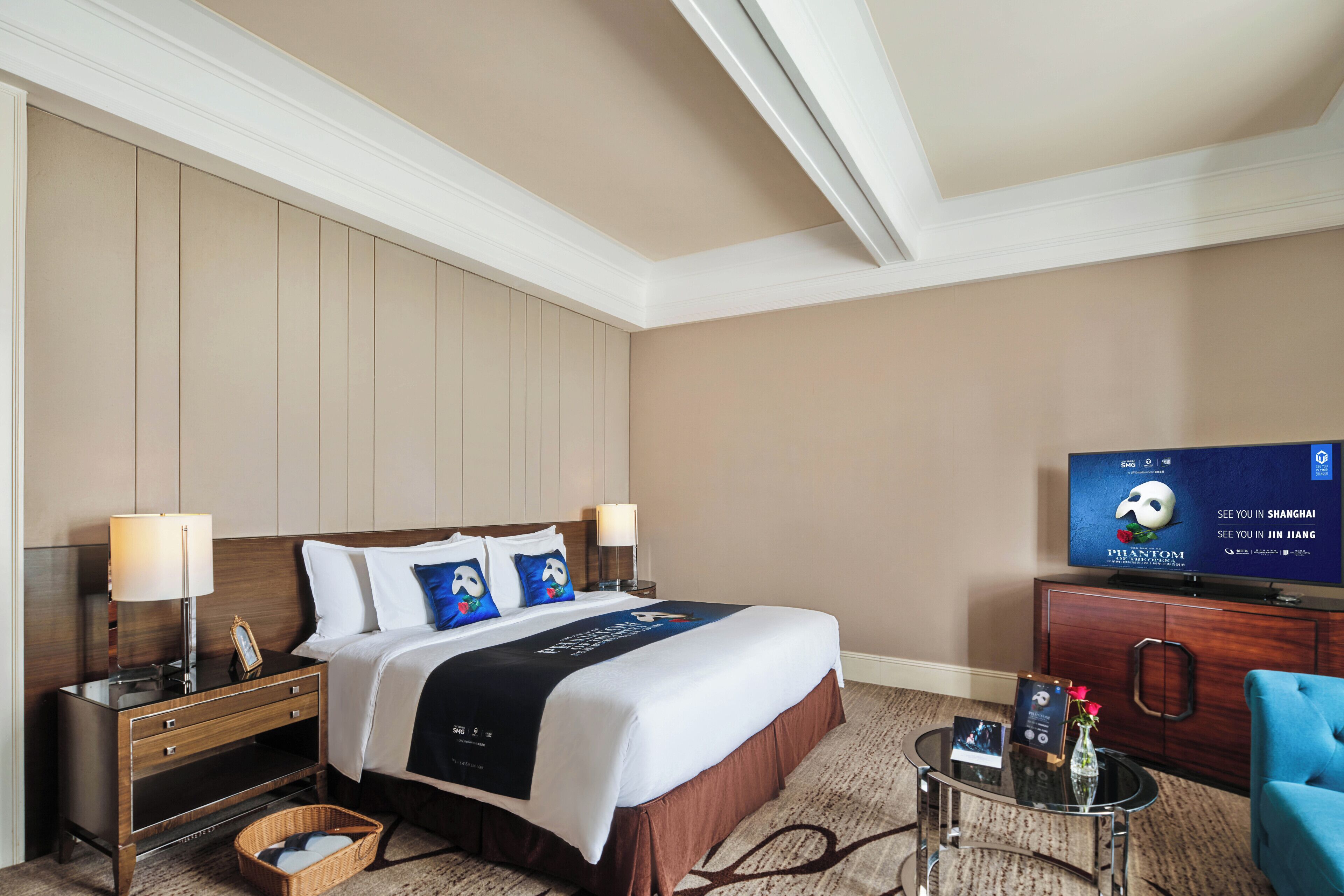 Een hotelkamer met een bed, nachtkastjes, een televisie, een stoel en een tafeltje met een vaas.