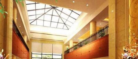A spacious lobby with a high ceiling, a skylight, and a balcony with a railing.