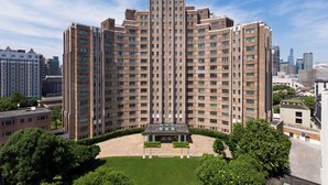 A high-rise building with a central courtyard, surrounded by greenery and other buildings. - Jin Jiang Hotel Shanghai (Shanghai)