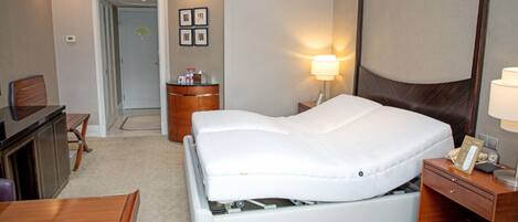 Ein Hotelzimmer mit Bett, Nachttisch, Lampe und Schreibtisch mit Stuhl.