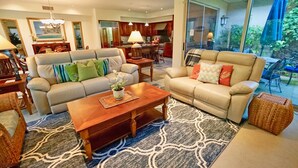 A spacious living room with a sofa, a coffee table, and a dining area in the background. - Villages at Mauna Lani (Kamuela)