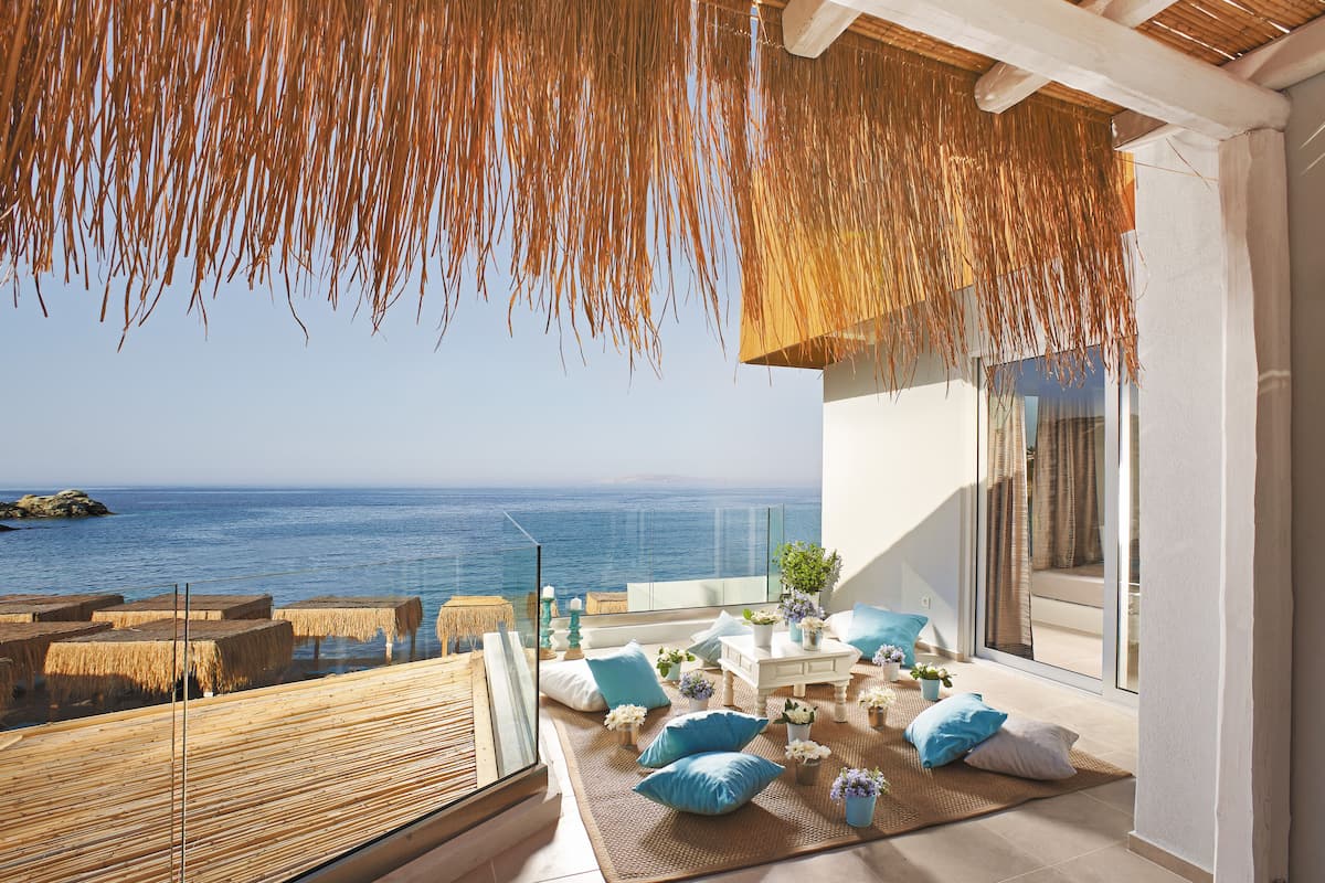 Un balcon donnant sur la mer, agrémenté de coussins et d’une table.