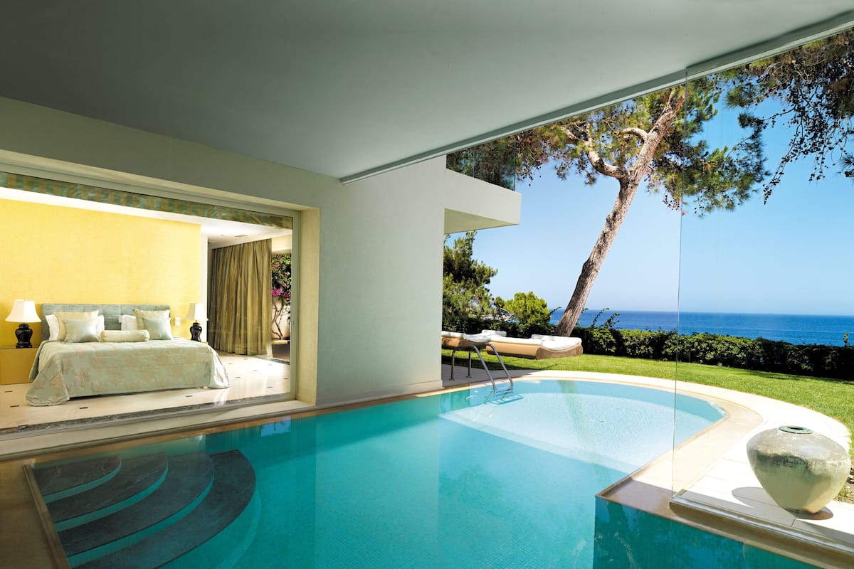 Une chambre moderne avec un grand lit, une vue sur l’océan et une piscine.