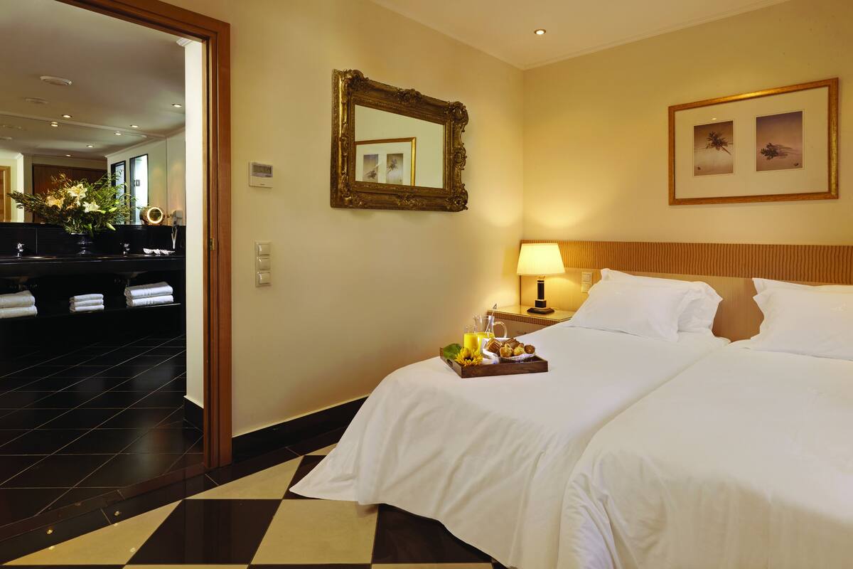 Une chambre d’hôtel avec un grand lit, une table de chevet avec une lampe, un miroir et un tableau encadré au mur.
