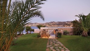 A stone pathway leading to a building with a view of the sea and hills in the background. - Out Of The Blue All Inclusive Resort & Spa (Malevizi)