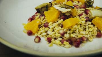 Un plato de comida con granos, semillas de granada y trozos de naranja.